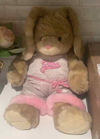 Souffle sitting against a wall wearing a silver jumpsuit with pink trim
